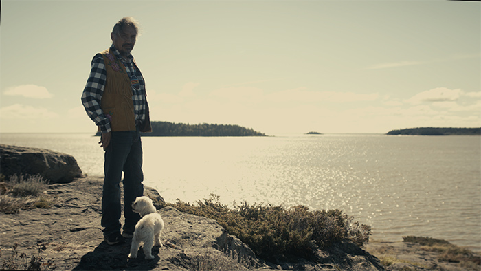 Still of man with dog at the edge of the Athabasca River