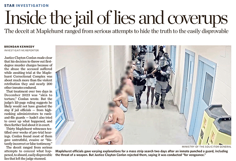 A row of inmates sits unclothed against a hallway wall as several officers in protective gear stand nearby inside a jail facility.